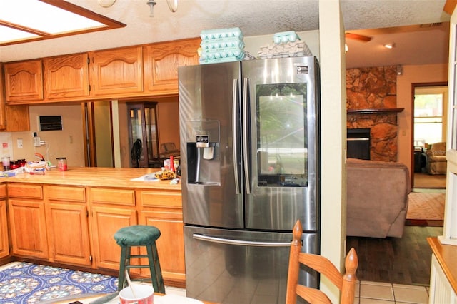 16536 Caldwell Ln, Spring Hill, FL 34610 - kitchen featuring stainless steel fridge, light countertops, light tile patterned floors, and brown cabinetry