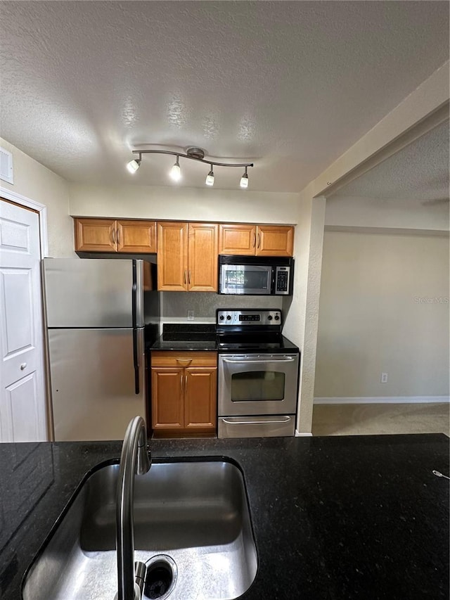 3260 Haviland Ct Unit 202, Palm Harbor, FL 34684 - kitchen with brown cabinets, a textured ceiling, appliances with stainless steel finishes, and a sink