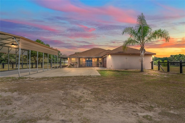 view of front of home with fence, a patio, stucco siding, driveway, and a detached carport