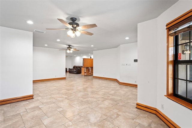 empty room with baseboards, ceiling fan, recessed lighting, and light stone finish floors
