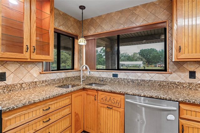 kitchen featuring dishwasher, a sink, and dark stone counters