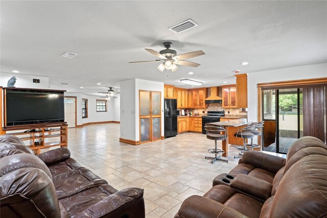 living room featuring a ceiling fan, baseboards, recessed lighting, and stone tile floors