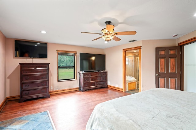 bedroom with wood finished floors, baseboards, recessed lighting, ensuite bath, and a baseboard heating unit