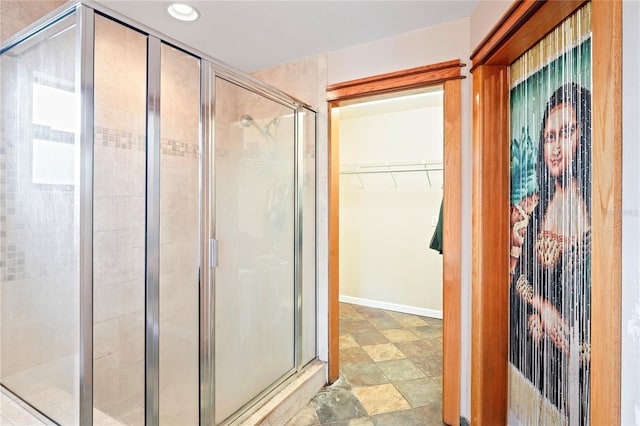 full bathroom with a shower stall, recessed lighting, a walk in closet, and baseboards