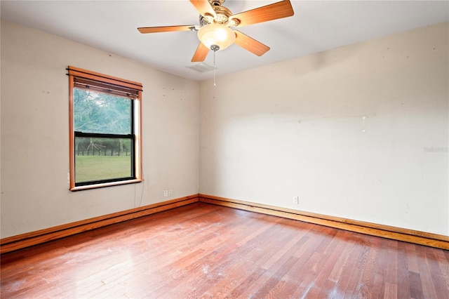 empty room with wood-type flooring, a ceiling fan, and baseboards