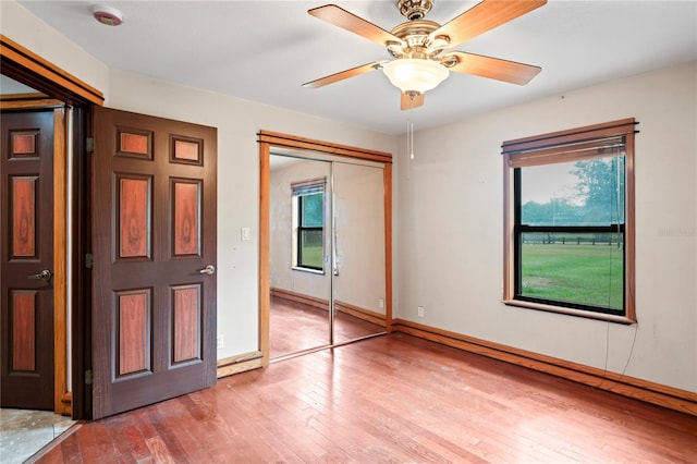unfurnished bedroom featuring wood-type flooring, baseboards, a closet, and a ceiling fan