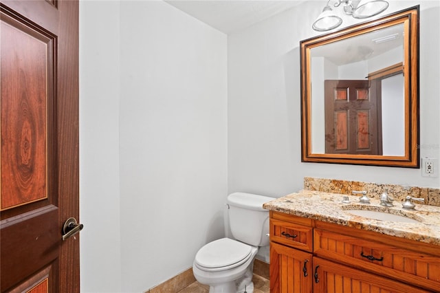 half bathroom featuring toilet, vanity, and baseboards