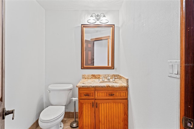 half bathroom with toilet, vanity, and baseboards