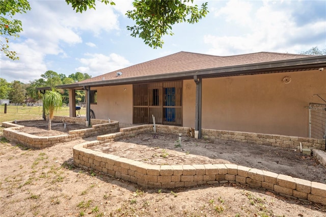 back of property with stucco siding and a shingled roof