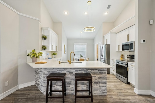 kitchen featuring visible vents, appliances with stainless steel finishes, open shelves, a sink, and a breakfast bar