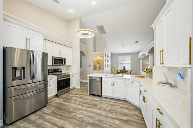 kitchen featuring arched walkways, a sink, white cabinetry, and stainless steel appliances
