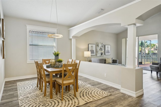 dining space featuring baseboards, decorative columns, wood finished floors, and a wealth of natural light