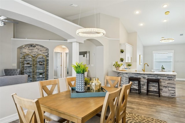 dining space featuring visible vents, wood finished floors, high vaulted ceiling, recessed lighting, and arched walkways