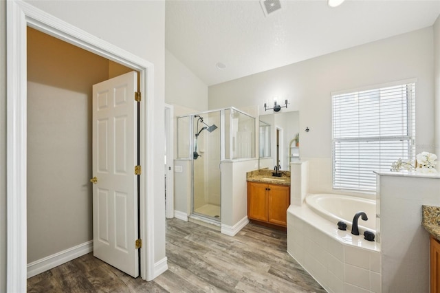 bathroom with visible vents, vanity, wood finished floors, a bath, and a stall shower