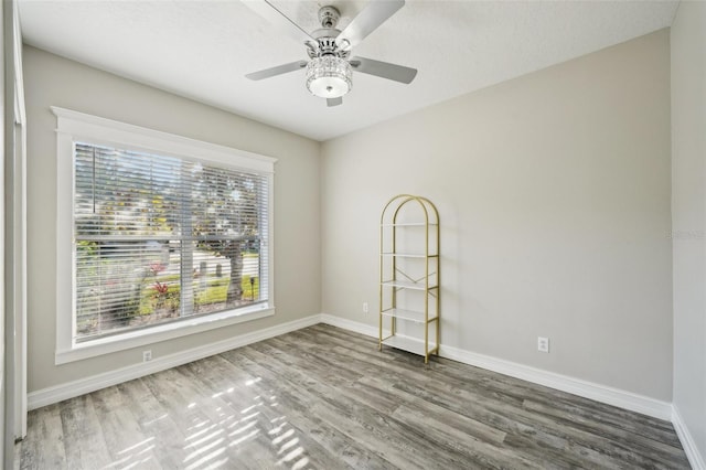 spare room featuring baseboards, ceiling fan, and wood finished floors