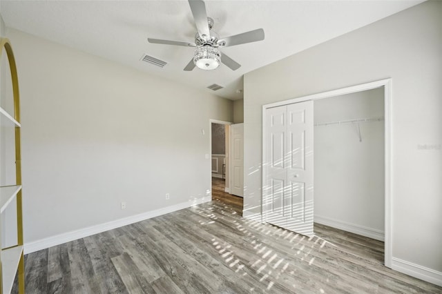 unfurnished bedroom featuring visible vents, baseboards, wood finished floors, and a closet