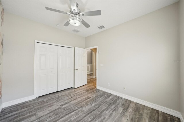 unfurnished bedroom featuring visible vents, baseboards, wood finished floors, and a closet