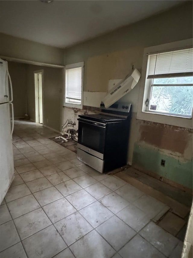 kitchen featuring light tile patterned floors, stainless steel electric range, and a wealth of natural light