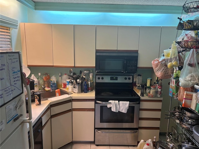kitchen with black microwave, light countertops, freestanding refrigerator, and electric stove