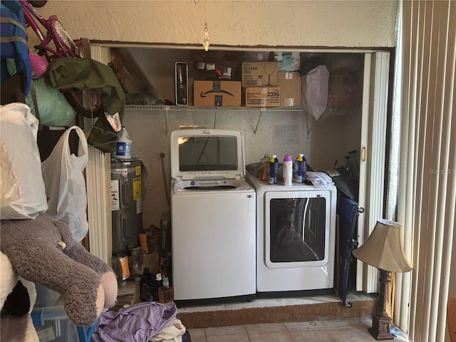 laundry area with laundry area, a textured wall, washer and clothes dryer, tile patterned floors, and water heater