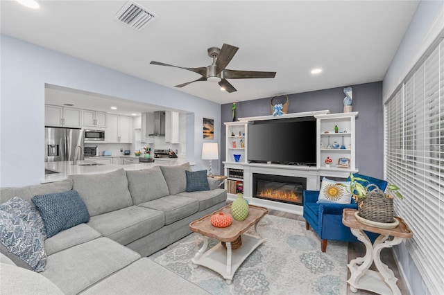297 Lakeview Dr, Tarpon Springs, FL 34689 - living room with ceiling fan, recessed lighting, a glass covered fireplace, and wood finished floors