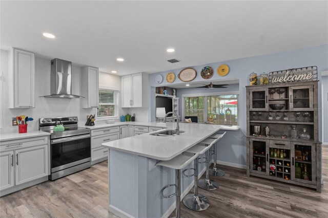 297 Lakeview Dr, Tarpon Springs, FL 34689 - kitchen with wall chimney range hood, stainless steel electric range oven, a sink, a breakfast bar, and a peninsula