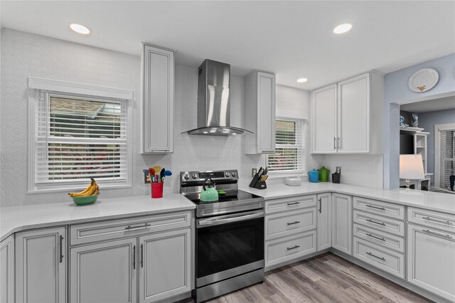 297 Lakeview Dr, Tarpon Springs, FL 34689 - kitchen with stainless steel electric stove, wall chimney exhaust hood, light countertops, light wood-style floors, and recessed lighting