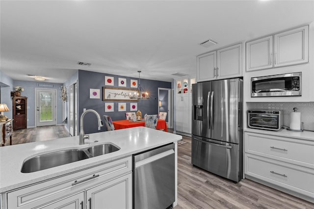 297 Lakeview Dr, Tarpon Springs, FL 34689 - kitchen featuring stainless steel appliances, a sink, light countertops, a chandelier, and light wood finished floors