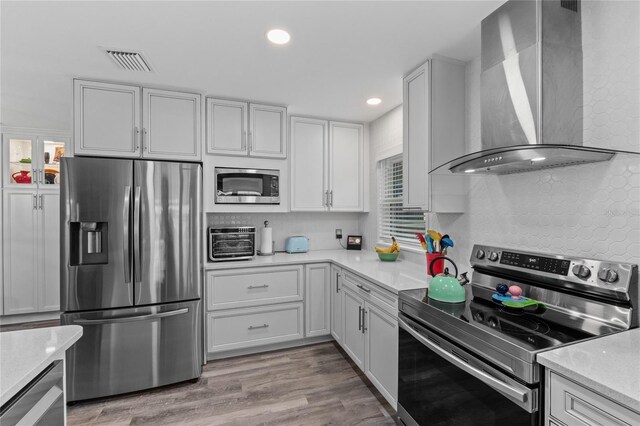 297 Lakeview Dr, Tarpon Springs, FL 34689 - kitchen with appliances with stainless steel finishes, wall chimney exhaust hood, plenty of natural light, white cabinets, and recessed lighting