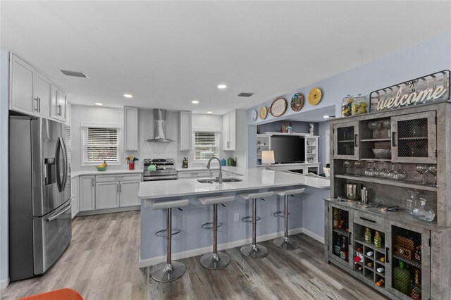 297 Lakeview Dr, Tarpon Springs, FL 34689 - kitchen with appliances with stainless steel finishes, wall chimney exhaust hood, a sink, a breakfast bar, and white cabinetry