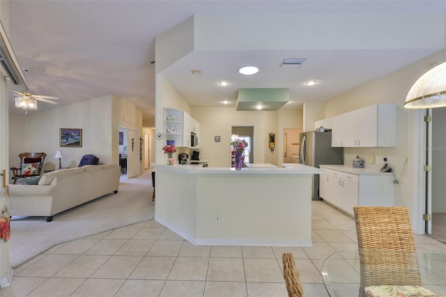 kitchen with light tile patterned floors, white cabinets, light carpet, and stainless steel appliances