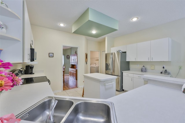 kitchen featuring stainless steel refrigerator with ice dispenser, washing machine and clothes dryer, open shelves, light countertops, and white cabinets