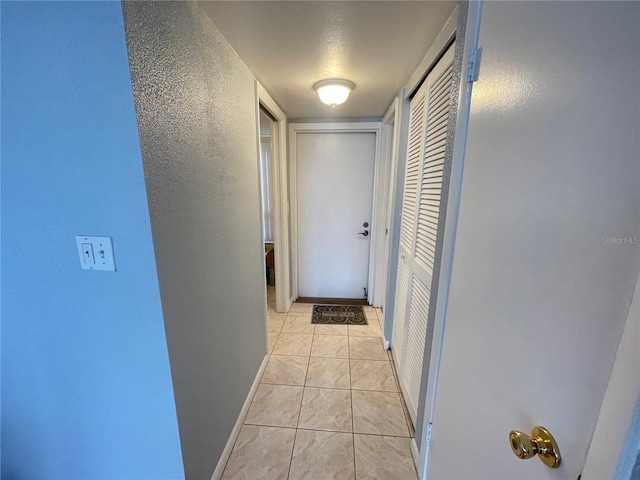 corridor with baseboards and a textured wall