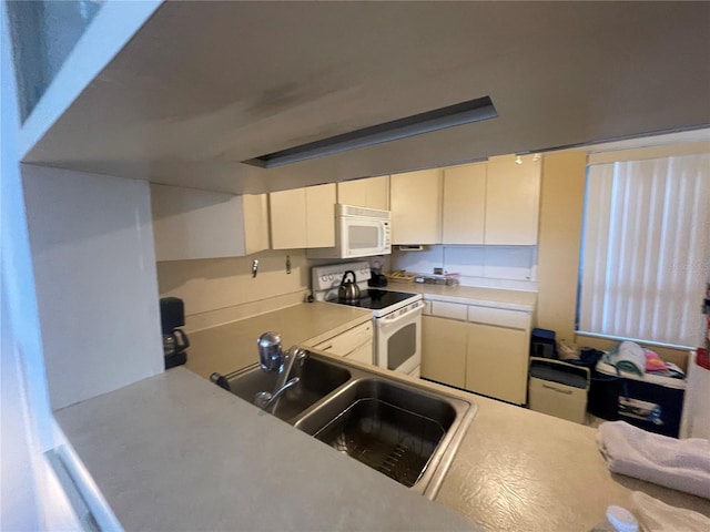 kitchen with a sink, light countertops, white appliances, and white cabinetry