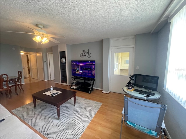living room with light wood-style floors, ceiling fan, and a textured ceiling