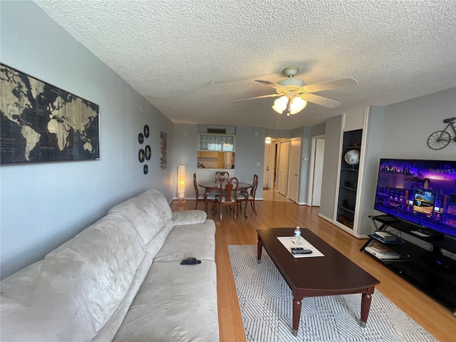 living room featuring a textured ceiling, ceiling fan, and wood finished floors