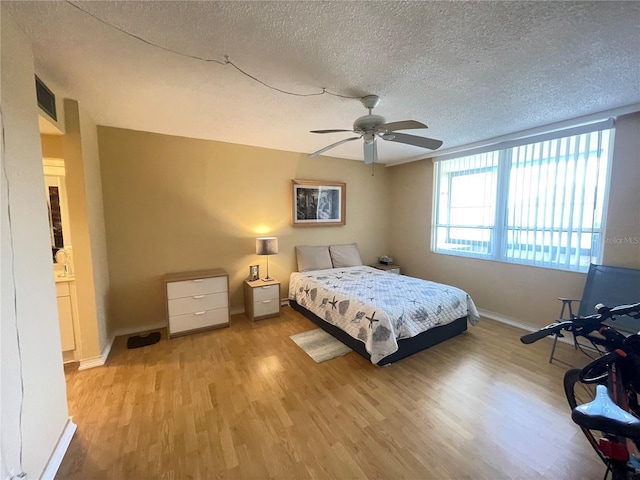 bedroom with baseboards, a textured ceiling, ceiling fan, and light wood-style flooring
