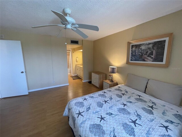bedroom featuring ensuite bath, a textured ceiling, baseboards, wood finished floors, and visible vents