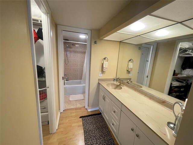 bathroom featuring vanity, shower / tub combo with curtain, a walk in closet, and wood finished floors