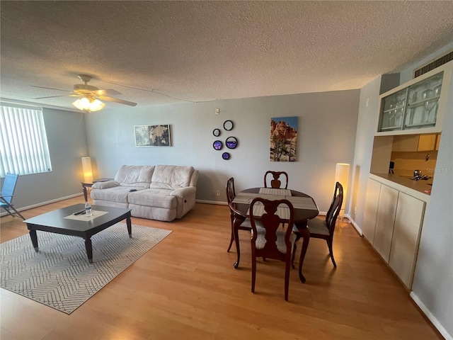 living room featuring light wood-style floors, baseboards, and a textured ceiling