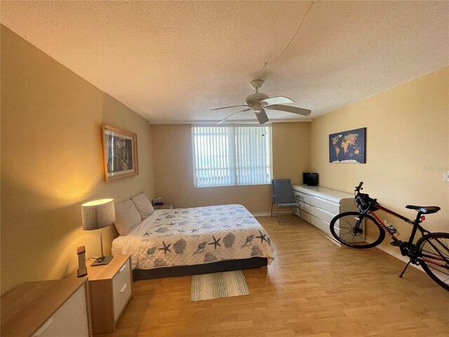 2615 Cove Cay Dr Unit 408, Clearwater, FL 33760 - bedroom featuring a textured ceiling, light wood-style floors, baseboards, and a ceiling fan