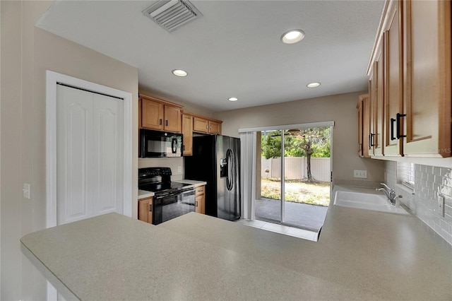 kitchen with visible vents, a peninsula, recessed lighting, a sink, and black appliances