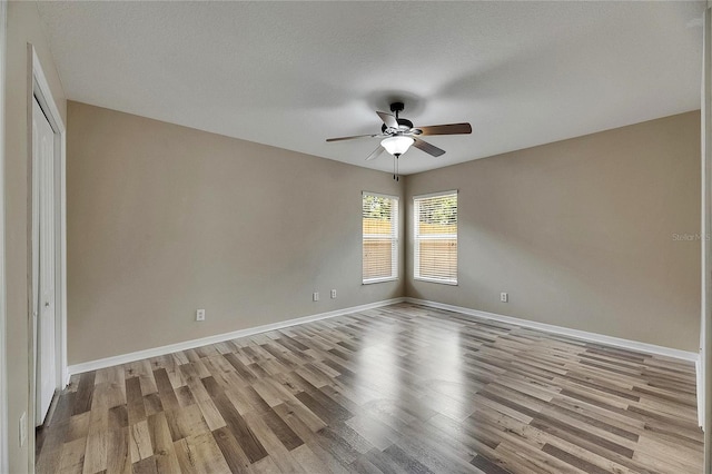 spare room with baseboards, a ceiling fan, and wood finished floors