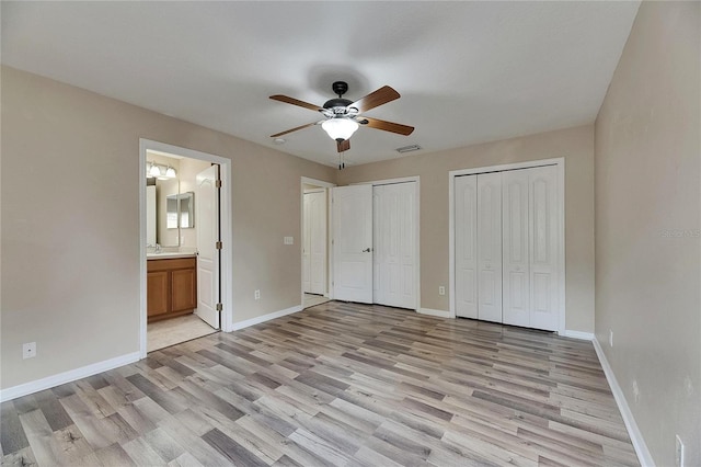 unfurnished bedroom with two closets, light wood-type flooring, and visible vents