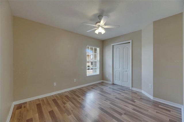 unfurnished bedroom with light wood-style floors, a ceiling fan, baseboards, and a closet