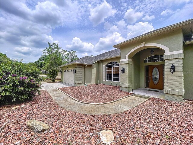 5058 Westlake Blvd, Dade City, FL 33523 - doorway to property with brick siding, an attached garage, and stucco siding