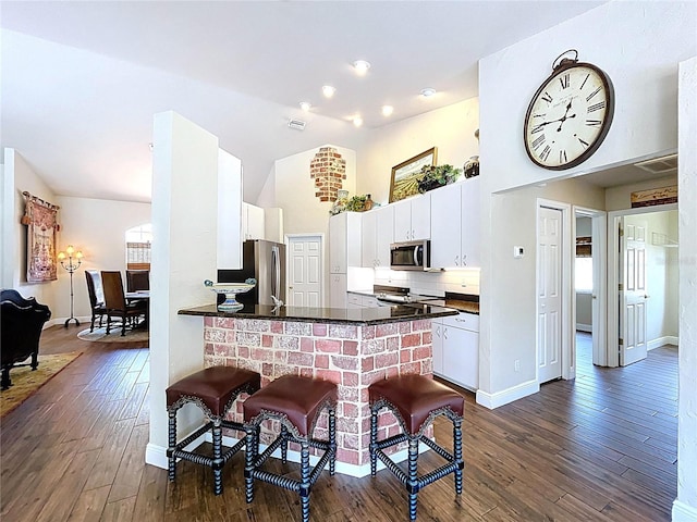 5058 Westlake Blvd, Dade City, FL 33523 - kitchen with appliances with stainless steel finishes, dark countertops, dark wood-type flooring, white cabinetry, and a peninsula