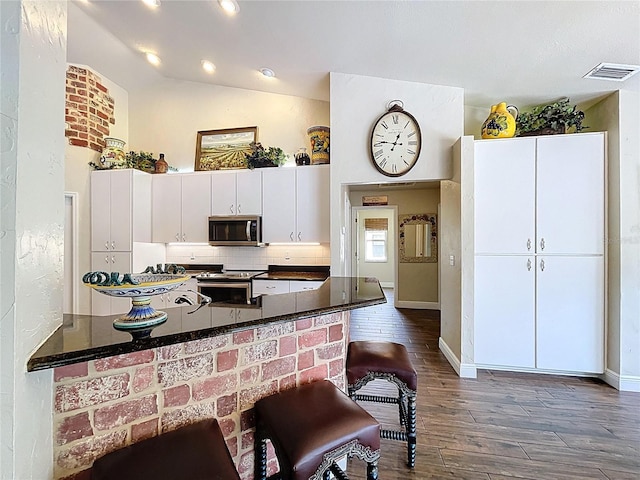 5058 Westlake Blvd, Dade City, FL 33523 - kitchen featuring appliances with stainless steel finishes, tasteful backsplash, dark wood finished floors, white cabinets, and baseboards