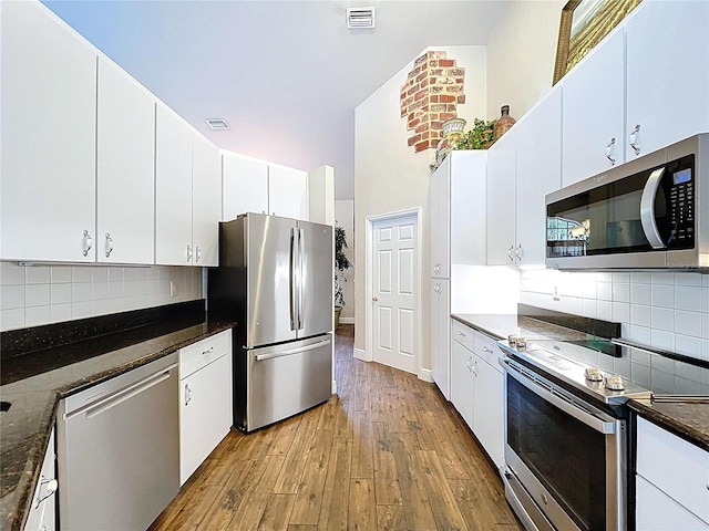 5058 Westlake Blvd, Dade City, FL 33523 - kitchen with stainless steel appliances, wood-type flooring, decorative backsplash, and white cabinets