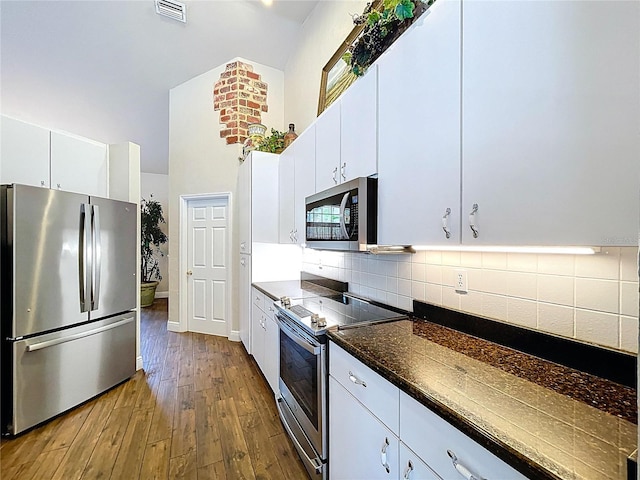 5058 Westlake Blvd, Dade City, FL 33523 - kitchen with appliances with stainless steel finishes, dark wood-style floors, tasteful backsplash, white cabinets, and a towering ceiling